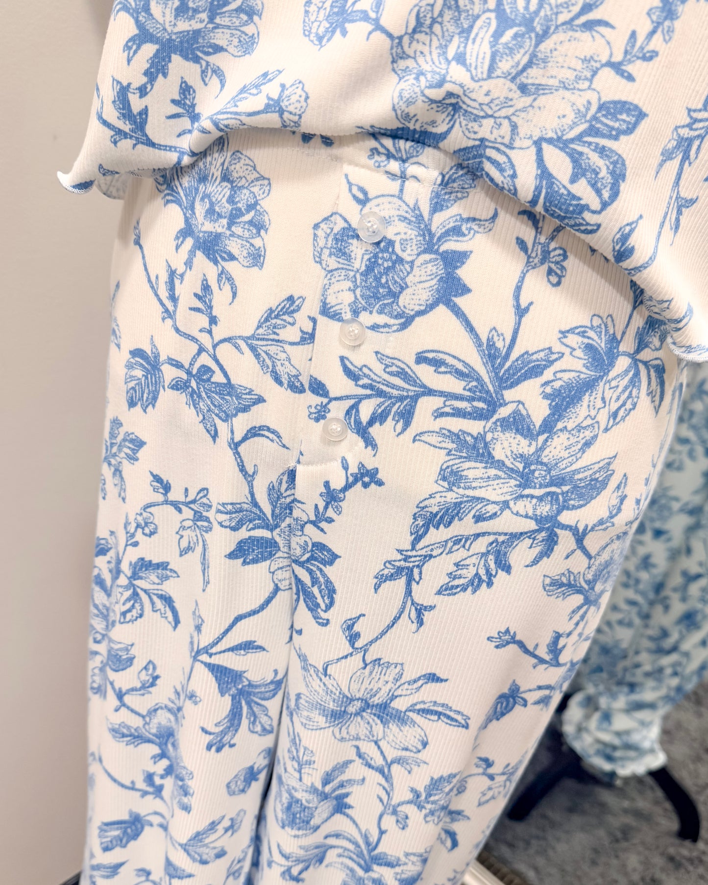 White pajama pants with blue floral pattern on a plain background