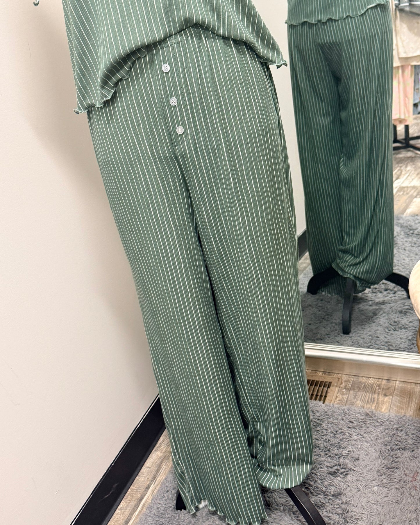 Green striped pajama pants with ruffled edges on a mirror.