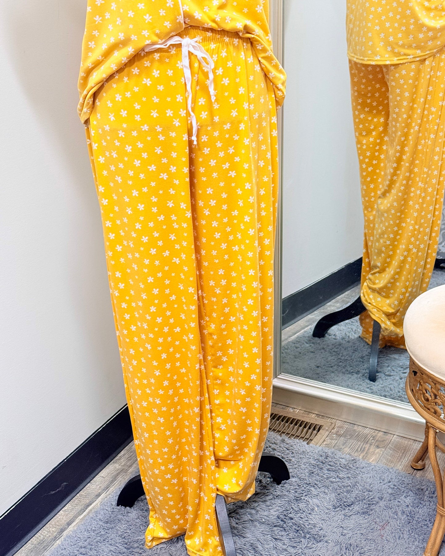 Yellow pajama set with small while flower pattern on a mannequin in front of a mirror.