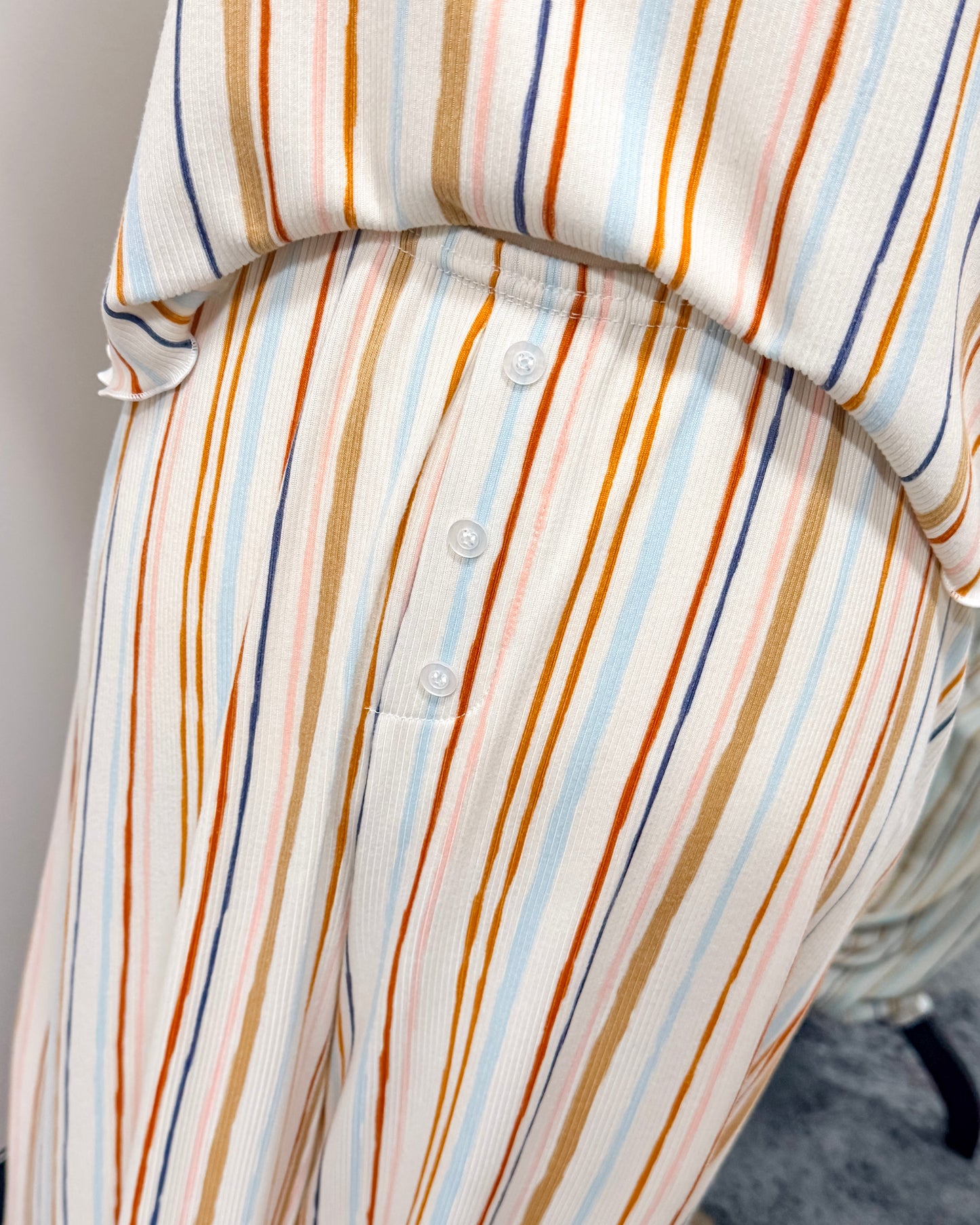 Close-up of a multicolored striped pajama pants with buttons on a neutral background