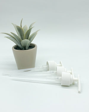 Three white liquid soap pumps lie next to a potted succulent.