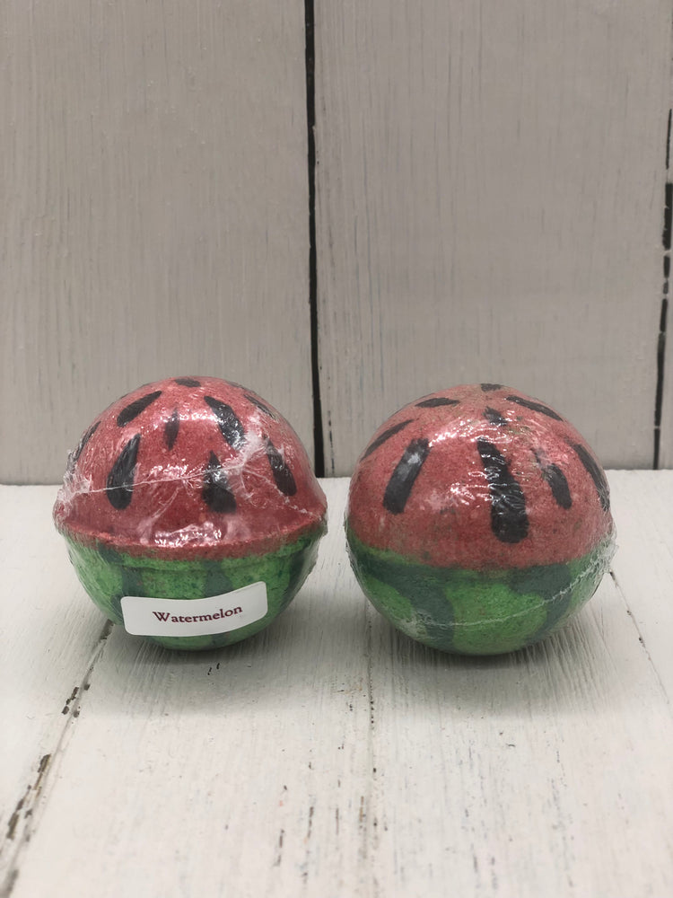 Watermelon bath bombs that are round and colored green on the bottom and painted like a watermelon rind then colored red on the top and painted with black watermelon seeds