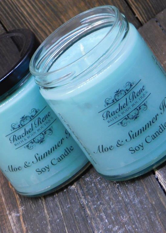 Teal candle in a stout glass jar with black lids labeled Aloe & Summer Herbs.