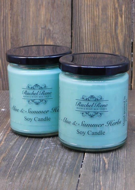 Teal candle in a stout glass jar with black lids labeled Aloe & Summer Herbs.