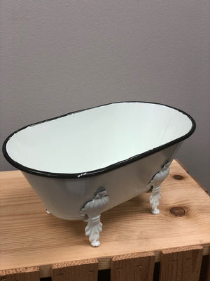 A medium white decorative bathtub to hold products with detailed footing and black trim on the top.