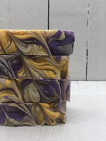A khaki colored soap bar with purple and gold swirls.