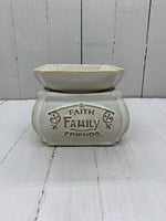 A ceramic wax warmer with the words "Faith, Family, Friends" written in gold on one side.