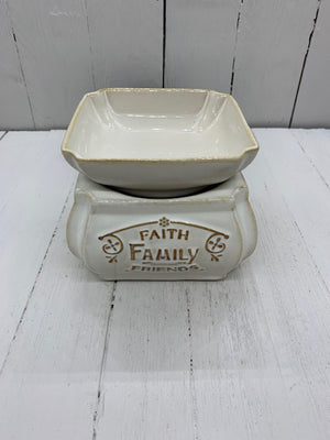A ceramic wax warmer with the words "Faith, Family, Friends" written in gold on one side. The camera is at a top down angle.