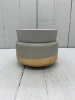 A gray ceramic wax warmer with a gold band on the bottom. There is a matching cup on top of the warmer.