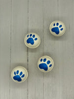 White bath bombs, some painted with blue paw prints, some painted with blue tiger stripes.