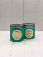 A clear plastic jar with teal jelly inside. There is a tan circular label that reads, "Aloe & Summer Herbs". There is a tin lid on top.